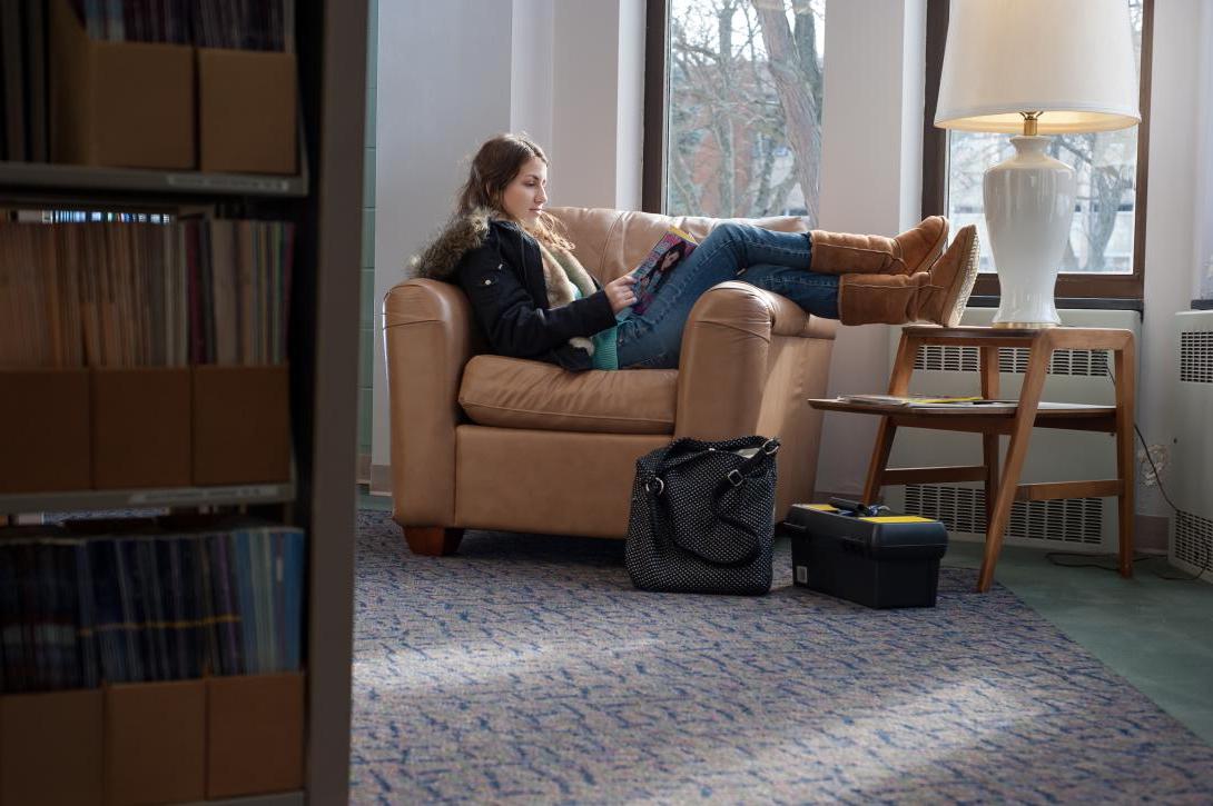 Student laying on a couch in the library studying